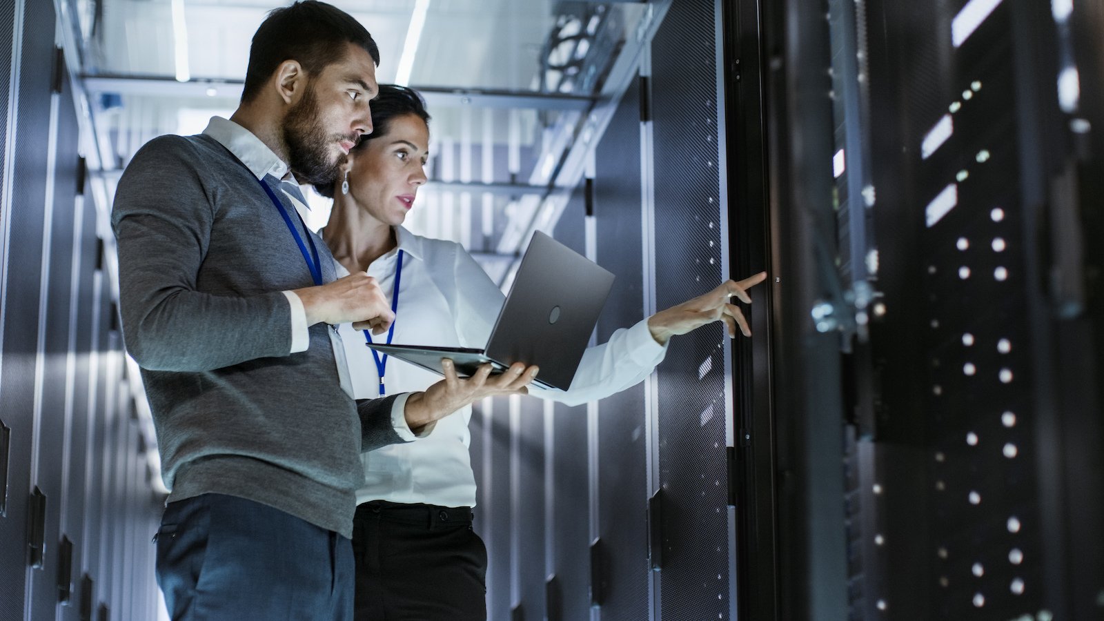 stock-photo-male-it-specialist-holds-laptop-and-discusses-work-with-female-server-technician-they-re-standing  1600-1